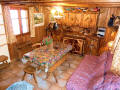 Salon du chalet individuel le Nid. Salon avec mobilier alpin rustique, grande table, canap-lit.